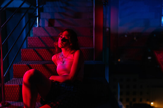 Unrecognizable woman sitting on stairs with a red light effect
