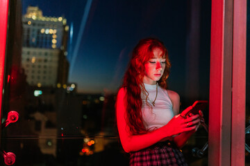 ginger woman using smart phone at night on bokeh background