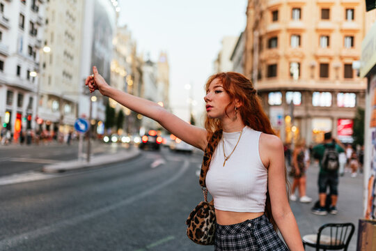 red hair young woman stopping a taxi on the street