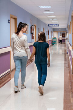 Mother and her daughter walking calmly across hospital hallway