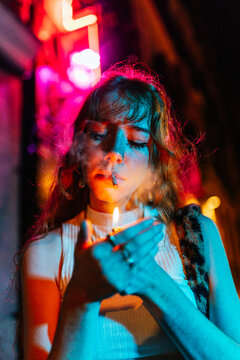 redhead woman lights a cigarette in the street at night