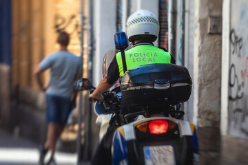 Spanish police squad formation on bike and motorcycle back view with "Local Police" logo emblem on uniform maintain public order in the streets of Alicante, Spain