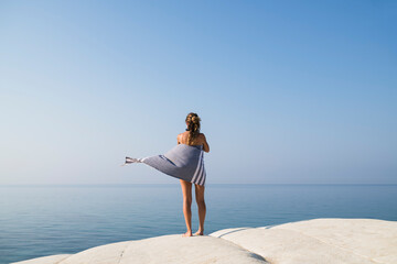 Young blonde woman relaxing on a white rock against deep blue se