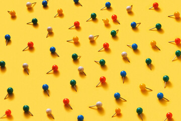 Decorative colorful office pins pattern on yellow.