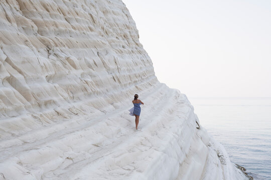 Woman walking on a white cliff against the sea
