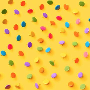 Office supplies pattern of colorful pins on yellow.
