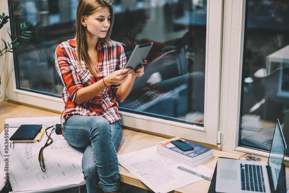 Poster pensive young woman reading information from website on modern tablet device using 4g internet durin