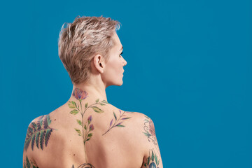 Beauty portrait of a young attractive half naked tattooed woman with perfect skin looking away,...