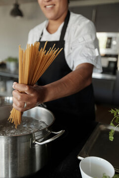 Woman Adding Spaghetti To Boiling Water