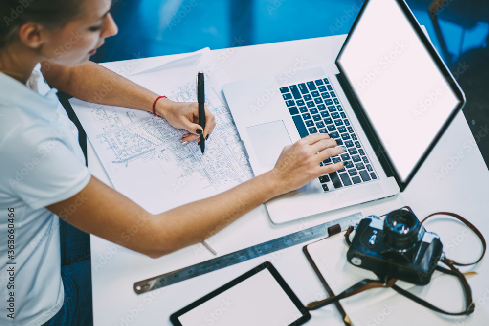 Poster cropped top view of student making measurements of building sketch while typing text on keyboard of 