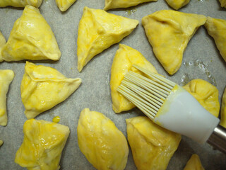 Homemade oiled pies are on a baking sheet on baking paper.