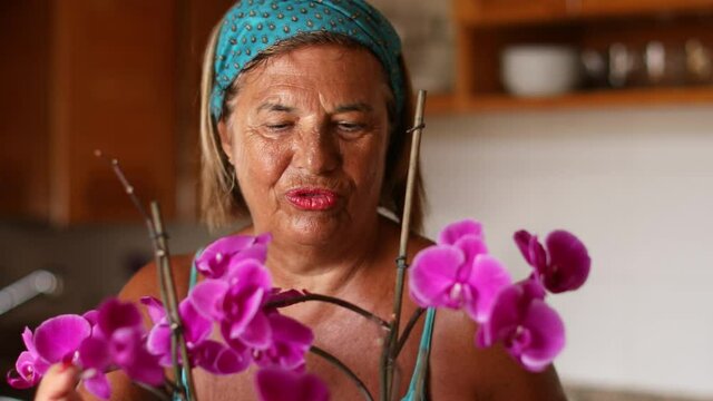 Video in 4k di Signora anziana che cura le sue orchidee in cucina