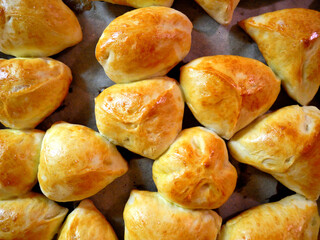 Baked pies with apples on a baking sheet. Homemade delicious pastries.