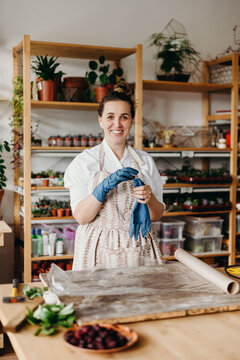 Portrait of a beauty caucasian woman in an apron in a crative studio. She is looking at the camera and smiling