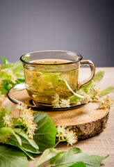Tilia platyphyllos known as large-leaved linden herbal tea made out of an freshly picked blossoms with tree leaves and branches with blossoms for decoration on wood table.