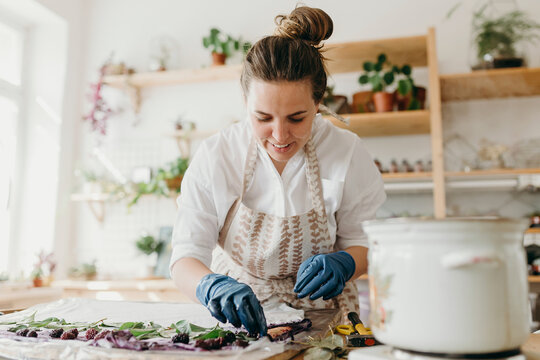 Woman in an apron in a creative process of creating a pattern on a white t-shirt