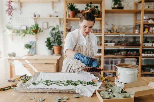 Woman in light clothes and in an apron in light room in a daylight. She is in an creative process.