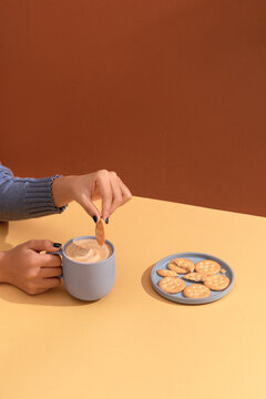 A hand holding a cookie, dipping it into coffee. Sweet homemade cookies