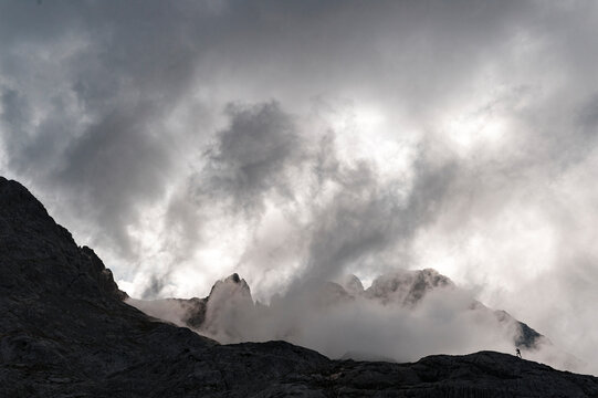 Silhouette of a trail runner running uphill in Picos de Europa National Park on a foggy day - Powered by Adobe