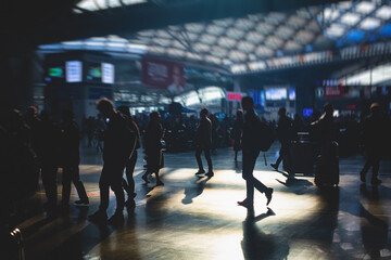 Fototapeta premium Indoor view of passenger terminal with people silhouettes walking by, train railway station with traveler silhouette crowd, modern terminus interior