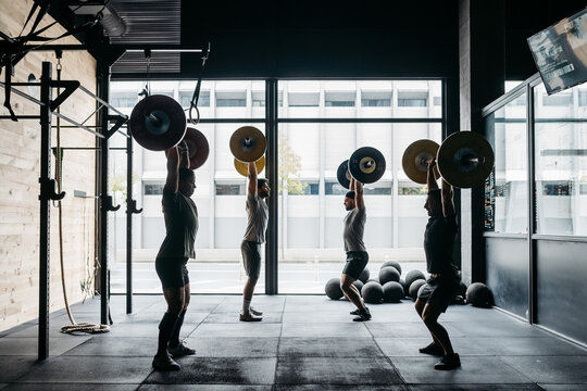 Men exercising with barbells in a crossfit box