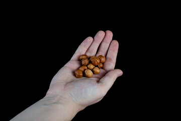 a handful of peeled hazelnuts in the palm, isolate on a black background