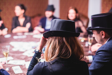 View of poker table with pack of cards, tokens, alcohol drinks, dollar money and group of gambling...