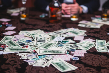 View of poker table with pack of cards, tokens, alcohol drinks, dollar money and group of gambling...