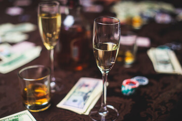 View of poker table with pack of cards, tokens, alcohol drinks, dollar money and group of gambling rich wealthy people playing poker