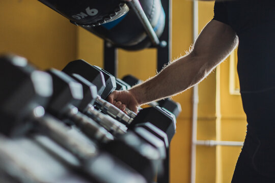 Strong and healthy man catching a dumbbell inside a crosffit gym