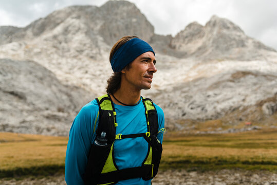 Trail runner resting in the meadows close to white limestone peaks in Picos de Europa National Park