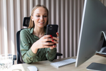 Young business woman working on line with a pc and phone in a desktop at office