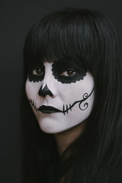 Elegant woman in Halloween black dress with sugar skull makeup