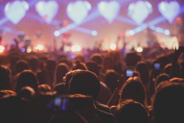 A crowded concert hall with scene stage lights, rock show performance, with people silhouette
