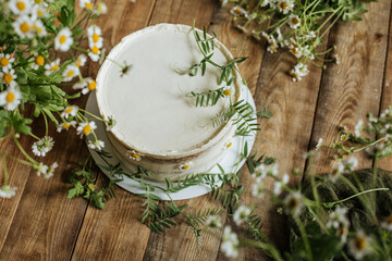 On the table is a cake decorated with chamomile flowers