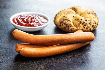 Fresh frankfurter sausages with bun and ketchup.