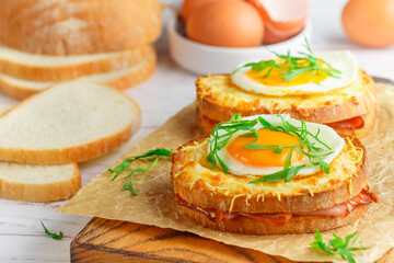 Sandwich white bread with ham or bacon, mustard, cheese, Bechamel sauce, watercress and eggs. CROQUE MADAME. traditional French cuisine. Selective focus