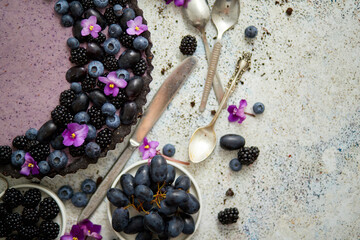 Sweet and tasty tart with fresh blueberries, blackberries and grapes, served on stone background