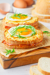 Sandwich white bread with ham or bacon, mustard, cheese, Bechamel sauce, watercress and eggs. CROQUE MADAME. traditional French cuisine. Selective focus
