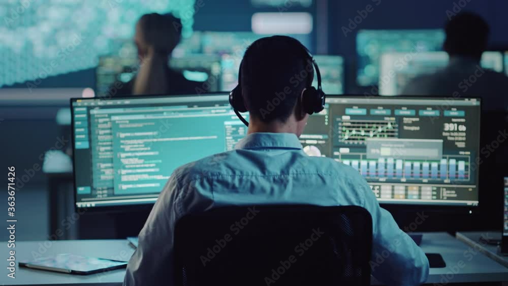 Poster Confident Male Data Scientist Works on Personal Computer in Big Infrastructure Control and Monitoring Room with Neural Network. Young Engineer in an Office Room with Colleagues.