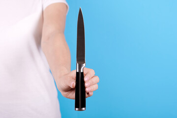 Hand with metallic kitchen knife. Isolated on blue background.