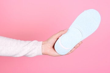 Hand with new cotton socks. Isolated on pink background.