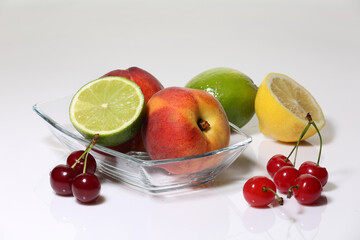 Peaches, limes and cherries on a light background