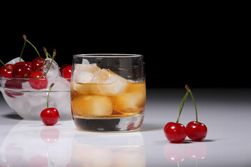Whiskey with ice and cherry berries on a dark background