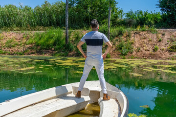 Young man in white pants and modern styling posing in the freshwater pond of Clot De La Mare De Deu in Burriana