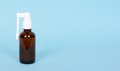 Medical throat spray in glass bottle, isolated on blue background, copy space.