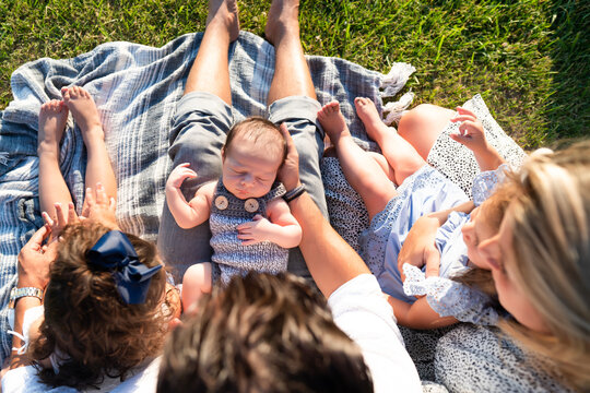 Family looking at newborn baby sleeping in father's arms - Powered by Adobe