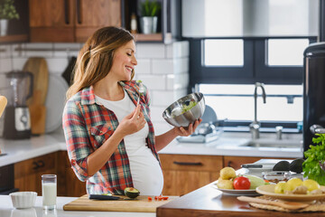 Beautiful pregnant woman preparing healthy meal with lots of vegetables at home