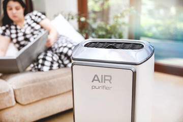 Air purifier cleans up air. Modern air purifier cleans up the air in the living room with woman...