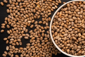 Carioquinha type beans over black background. Brazilian beans. Top view